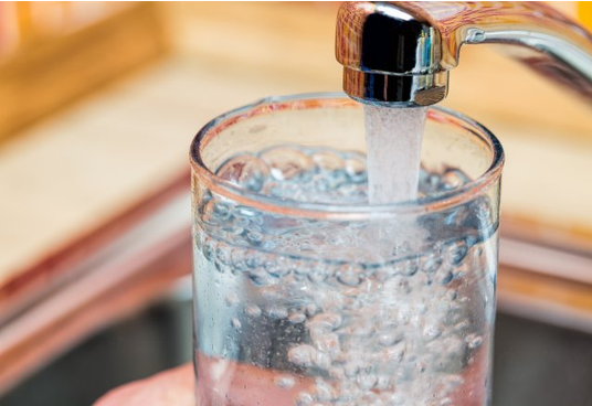 Glass of water filling from a tap
